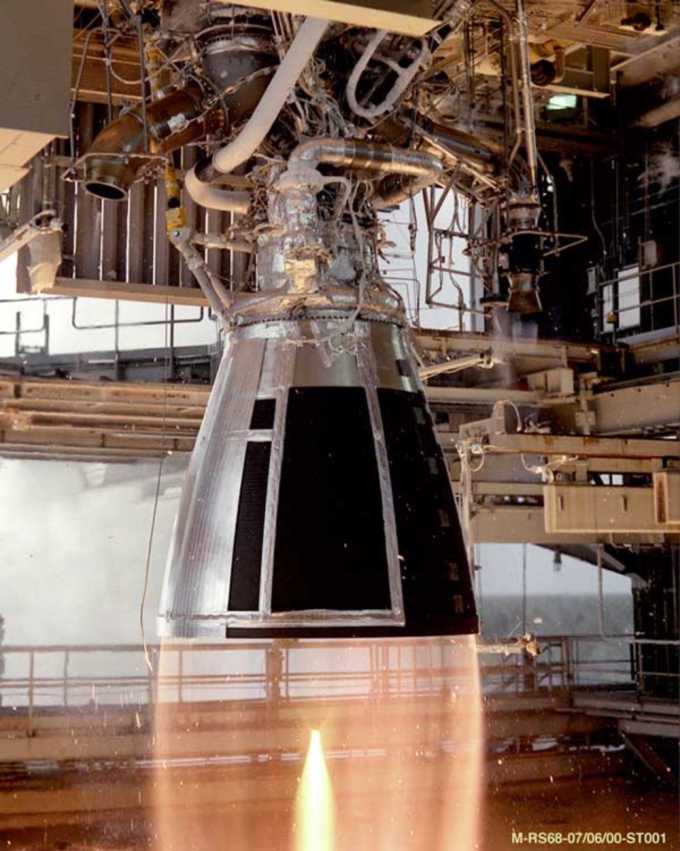 A SpaceX Raptor engine fires in a test stand, with a bright supersonic plume.